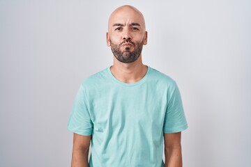 Middle age bald man standing over white background puffing cheeks with funny face. mouth inflated with air, crazy expression. - obrazy, fototapety, plakaty