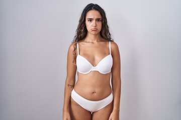 Obraz premium Young hispanic woman wearing white lingerie depressed and worry for distress, crying angry and afraid. sad expression.