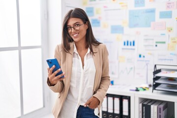 Young beautiful hispanic woman business worker smiling confident using smartphone at office