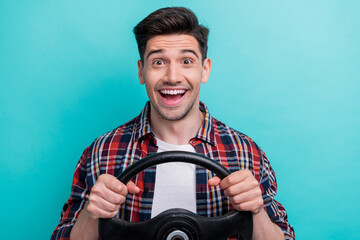 Photo of excited cheerful man dressed plaid shirt smiling driving auto isolated turquoise color background