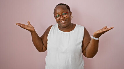 Clueless african american woman, standing over a pink isolated background, uncertain expression...
