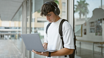 Cool young hispanic dude, a smart university student, lost in music through laptop, chilling...