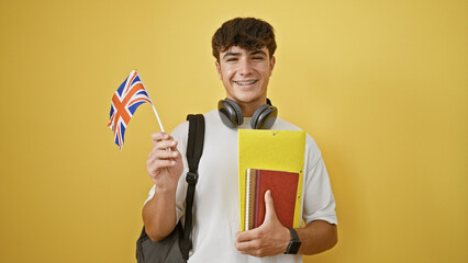 Smiling young hispanic teenager guy standing casual, smart student with books, uk flag in hand over...