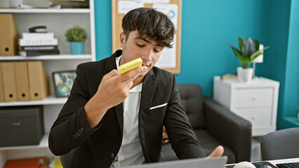 Hardworking young hispanic teenager thriving in business world, sending crucial voice message via smartphone at the office