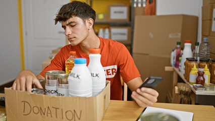 Dedicated young hispanic teenager volunteer working with passion, thoroughly checking food products...
