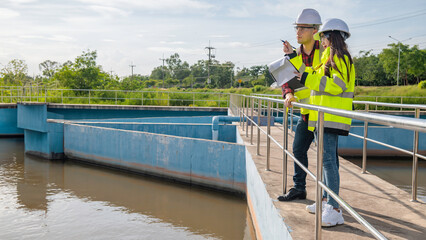 Environmental engineers work at wastewater treatment plants,Water supply engineering working at Water recycling plant for reuse,Technicians and engineers discuss work together. - obrazy, fototapety, plakaty
