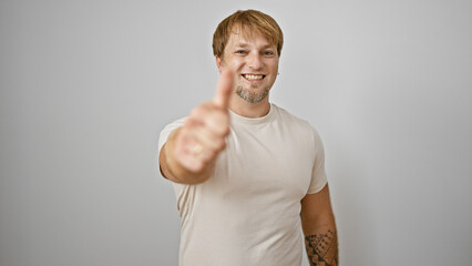 A cheerful young man with a beard and tattoo giving a thumbs up against a white background.