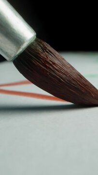 Vertical video. First-person view, macro shots of the artist's brush, painting with red paint on a black background.