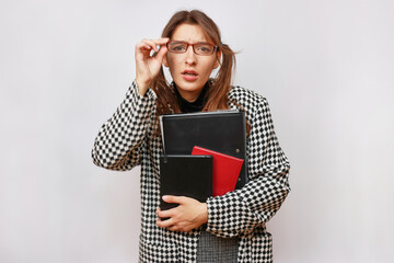 A student in glasses and a backpack holds books in her hands.