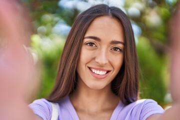 Young beautiful hispanic woman smiling confident making selfie by camera at park