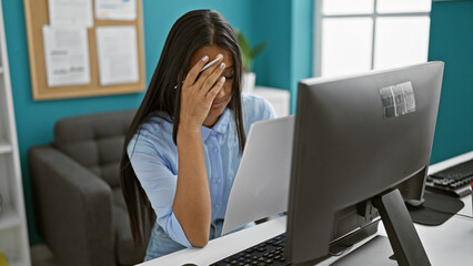 Young latin woman business worker using computer reading document looking upset at the office