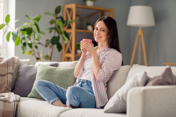 Full size portrait of positive nice girl sit comfy sofa crossed barefoot legs hold fresh coffee mug pastime flat indoors