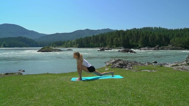 Yoga session in mountain river view. Young athletic girl training in cliffy mountains during sunrise, doing various yoga poses - healthy lifestyle concept 4k footage