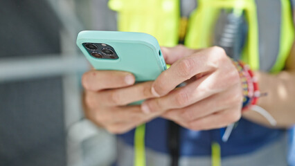 Young hispanic man architect using smartphone at construction place