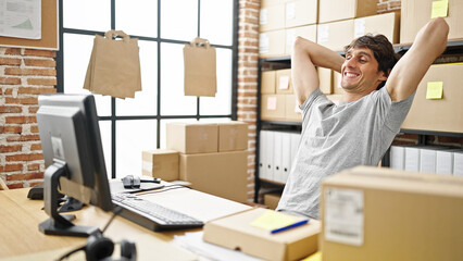 Young hispanic man ecommerce business worker relaxing with hands on head at office