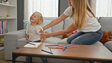 Relaxed caucasian mother and her little girl confidently sharing smiles indoors, comfortably sitting on living room sofa encapsulating family lifestyle.