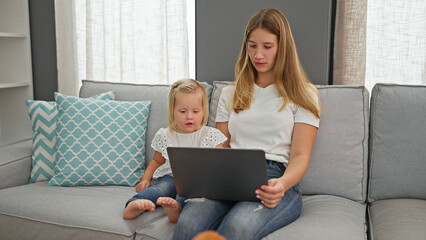 Serious caucasian mother and little daughter engrossed, chilling on their living room sofa at home,...