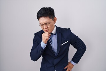 Young asian man wearing business suit and tie feeling unwell and coughing as symptom for cold or...