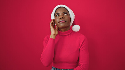 African american woman wearing christmas hat with doubt expression over isolated red background
