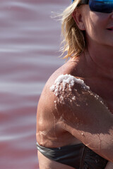 Mature woman relax in salty pink pool at wellness resort, sea salt crystals on her shoulder....