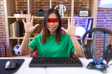 Middle age chinese woman wearing virtual reality glasses showing and pointing up with fingers...
