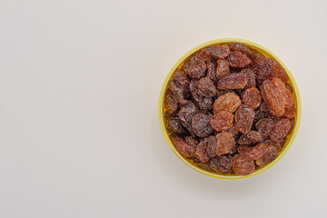 Raisins in a bowl on a white background, with copy space.