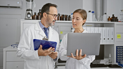 In the heart of the lab, two scientists engrossed in reading a medical document on clipboard,...