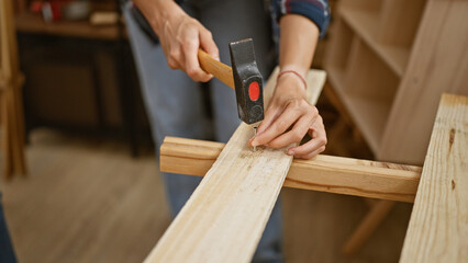 Two skilled carpenters, a dynamic duo, driving a nail into a wood plank at a lively carpentry...