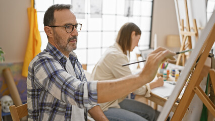 Obraz premium In an art studio, two focused artists - a man and woman, intently draw on canvas, deepening their bond and igniting creativity
