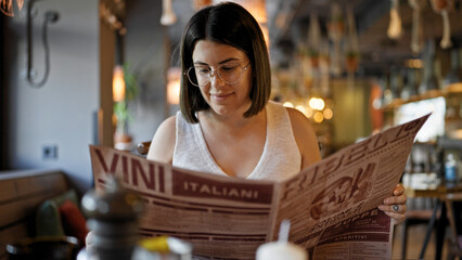 Young beautiful hispanic woman looking at restaurant menu at the restaurant