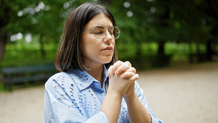 Fototapeta premium Young beautiful hispanic woman praying with closed eyes at the park in Vienna