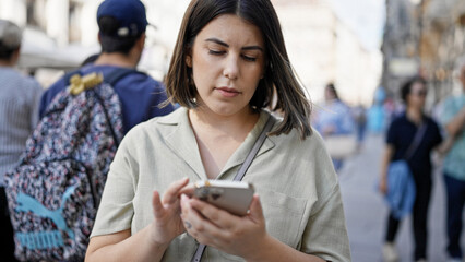 Young beautiful hispanic woman using smartphone in the streets of Vienna