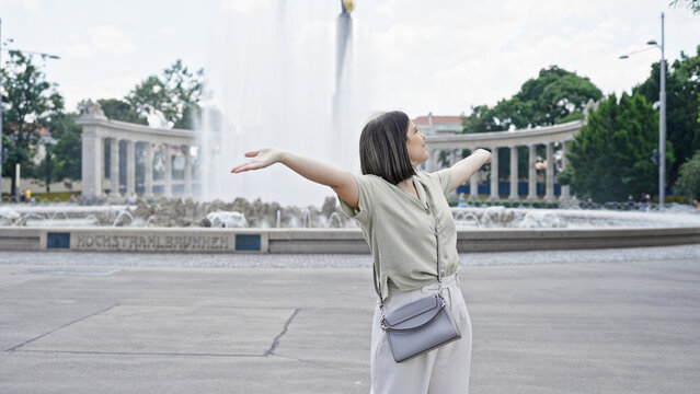 Young beautiful hispanic woman with open arms at Vienna fountain