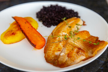 Delicious and healthy real food, grilled tilapia fish with black rice and sautéed vegetables