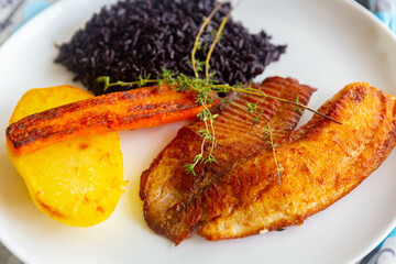 Delicious and healthy real food, grilled tilapia fish with black rice and sautéed vegetables