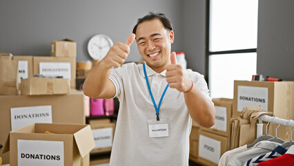 Smiling, confident young chinese man gives a jolly thumbs up gesture while volunteering at the...