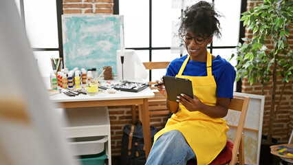 African american woman artist drawing on touchpad smiling at art studio