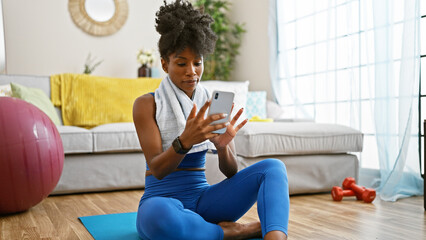 African american woman wearing sportswear using smartphone at home
