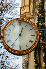 Fototapeta na wymiar A big clock in a rich district of the streets of Prague. The clock is mounted on a wall of a building