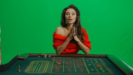 Gorgeous female in studio on chroma key green screen. Appealing woman in red dress sitting at the...