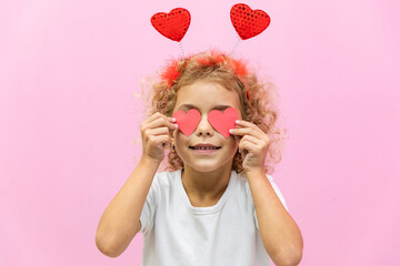 Beautiful little girl close eyes with red heart shaped greeting card. Portrait of child on pink. Paper cut valentine, handmade present. Saint Valentine's Day concept, holiday of all lovers.