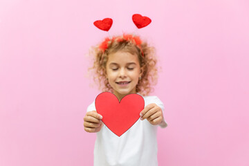 Selective focus beautiful little girl with red heart shaped greeting card. Portrait of child on...