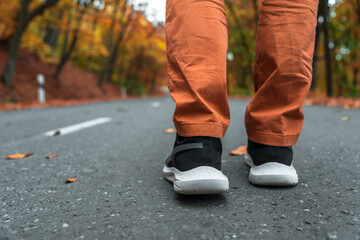 Autumn Day: Person Walking on Yellow Leaf-Covered Road Wearing  Sports Shoes