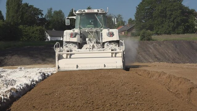 Industrial machinery doses and mixes the soil with lime for stabilization