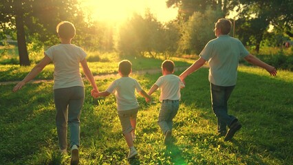 Family Dad, mother, child, son run together. Happy family, holding hands, runs towards sun, has fun...