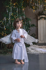 boy in white with wings in Christmas studio