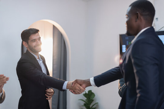 Businessmen shake hands and congratulate each other in the conference room.