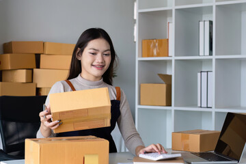 Startup SME small business entrepreneur SME or freelance Asian woman using a laptop with box, online marketing packaging box and delivery, SME concept.