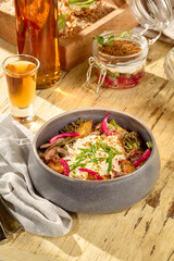 Hearty salad with roasted potatoes, shredded beef, onions, and smoked sour cream in a modern bowl