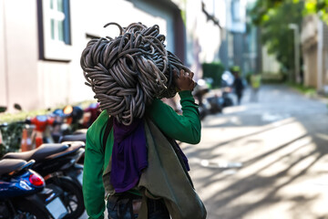 Fototapeta premium High rise hard work man carrying rope access on shoulder preparing to work on high rise building cleaning